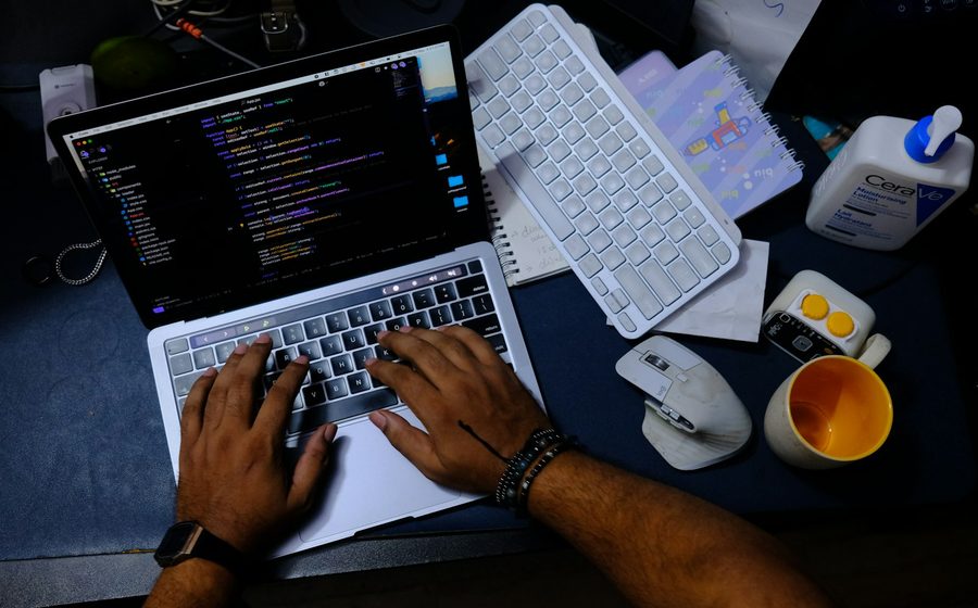Écran affichant du code, mains en train de reconstruire un site